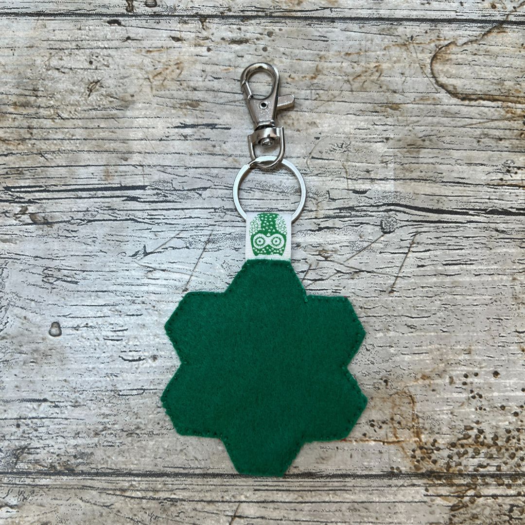 Green geometric keychain on a wooden surface
