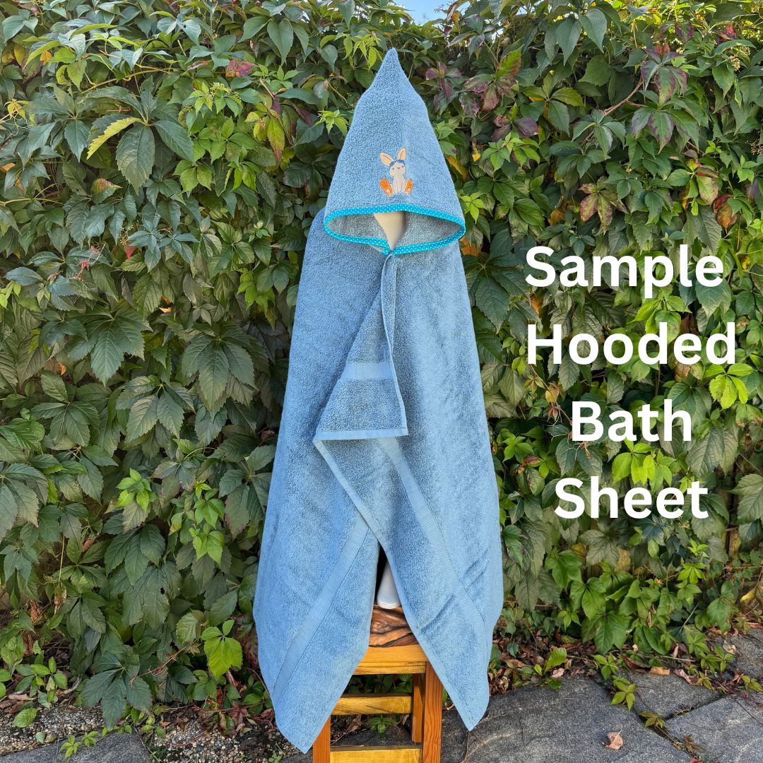 Blue hooded bath sheet on a wooden stool against a green leafy background