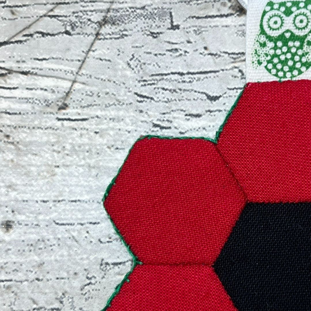 Close-up of red fabric with green trim on a textured surface