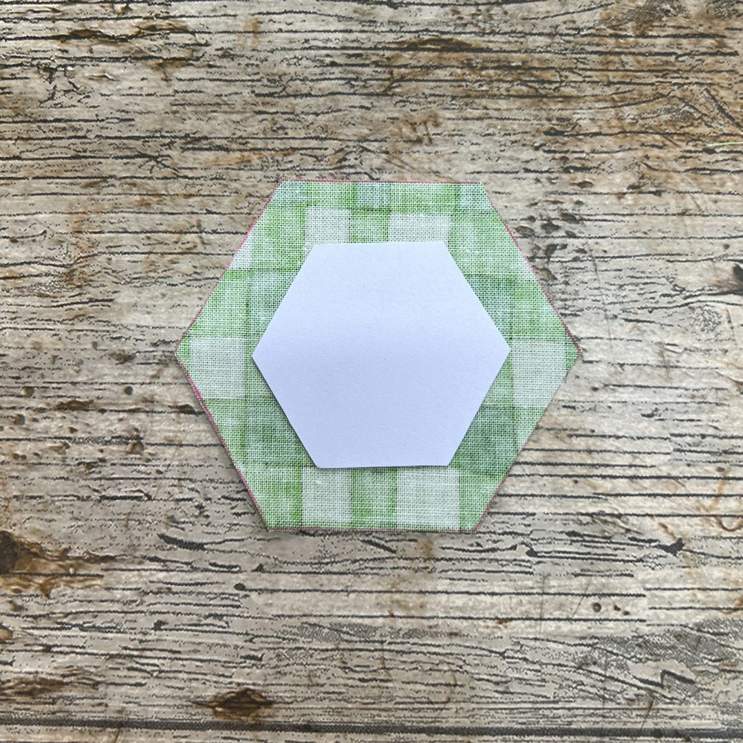 Hexagonal green fabric patch on a wooden surface