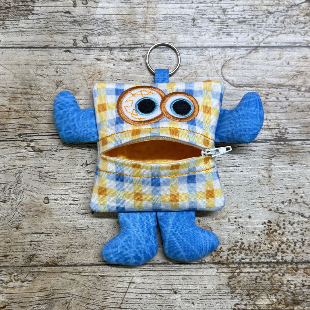 Money monster purse keychain with a checked pattern on a wooden surface