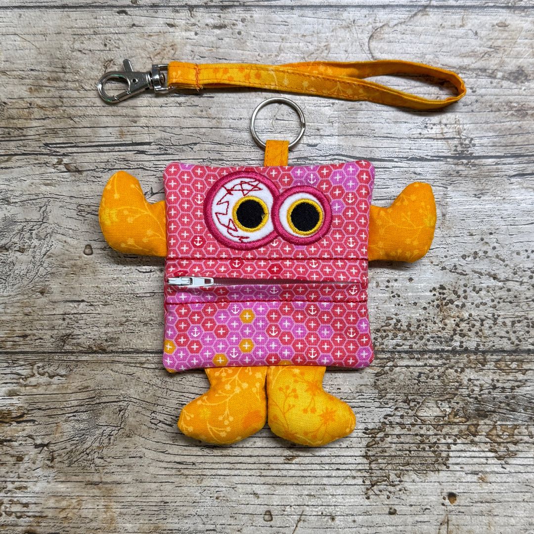 Pink Money Monster purse pouch with yellow accents on a wooden surface