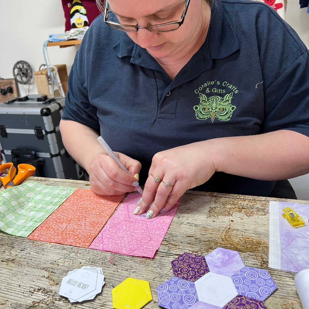 Person working on a craft project with fabric pieces on a wooden table.