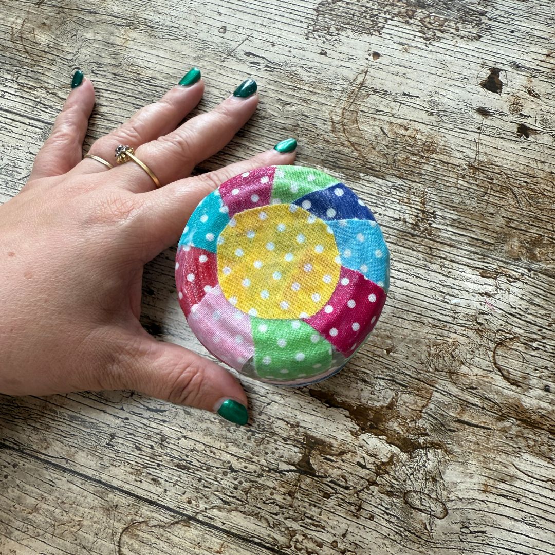 Colourful polka dot fabric on the bottom of a glass jar.