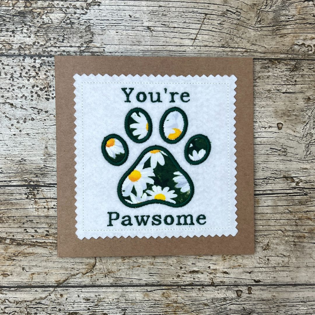 Card with paw print design and text 'You're Pawsome' on a wooden surface