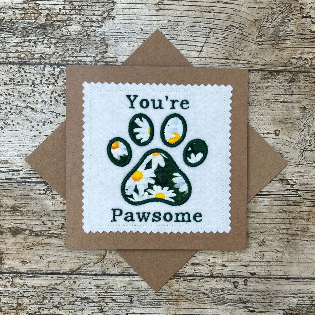 Card with paw print design and text 'You're Pawsome' on a wooden surface