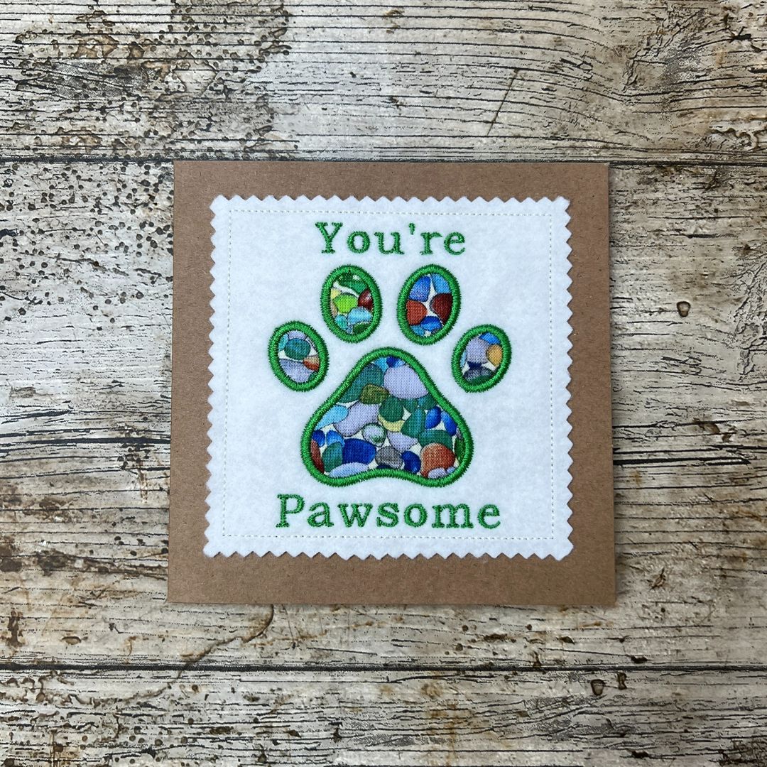 Card with paw print design and 'You're Pawsome' text on a wooden surface