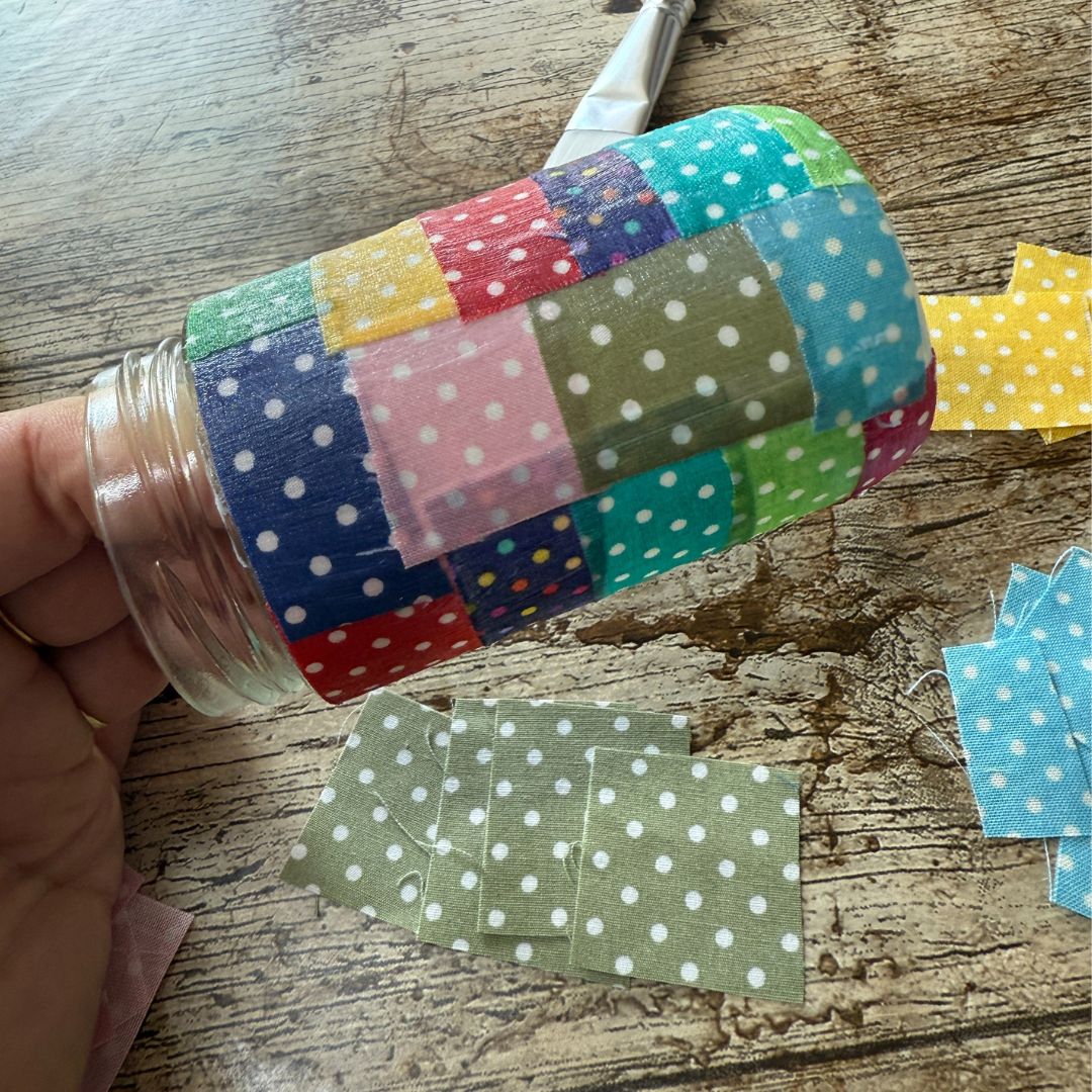 Colourful polka dot fabric on a glass jar on a wooden surface