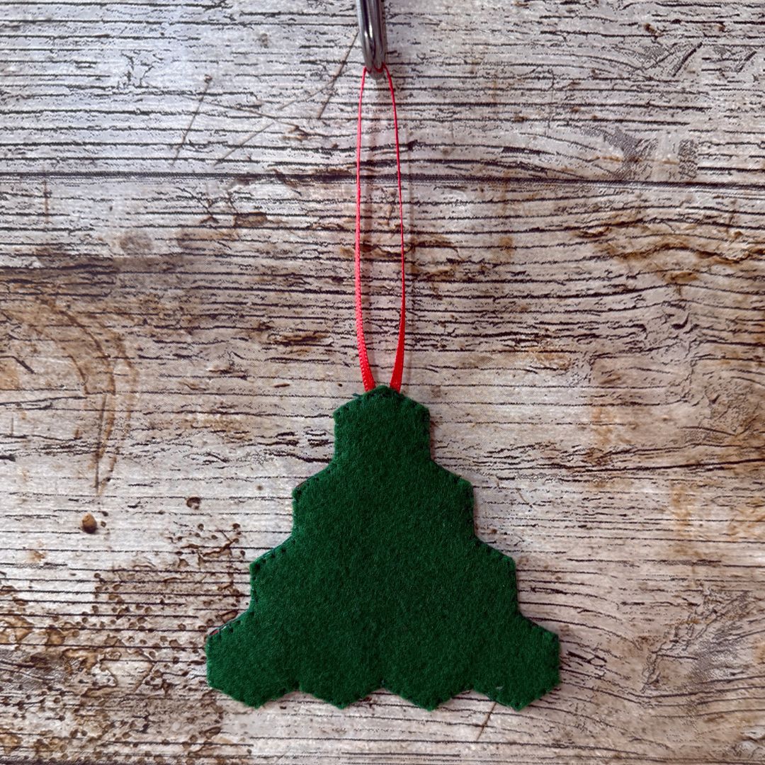 Green felt Christmas tree ornament on a wooden surface