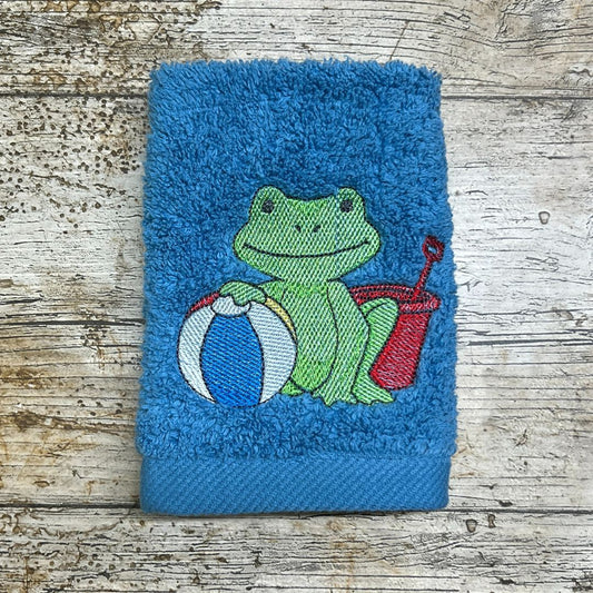 this super smiley frog is definitely ready for a day at the beach, and always looks super smart embroidered onto face cloths by Coralie's Crafts & Gifts in Blandford Dorset