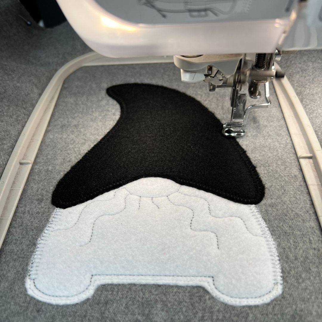 Black and white Gonk hat and body being embroidered on a embroidered machine