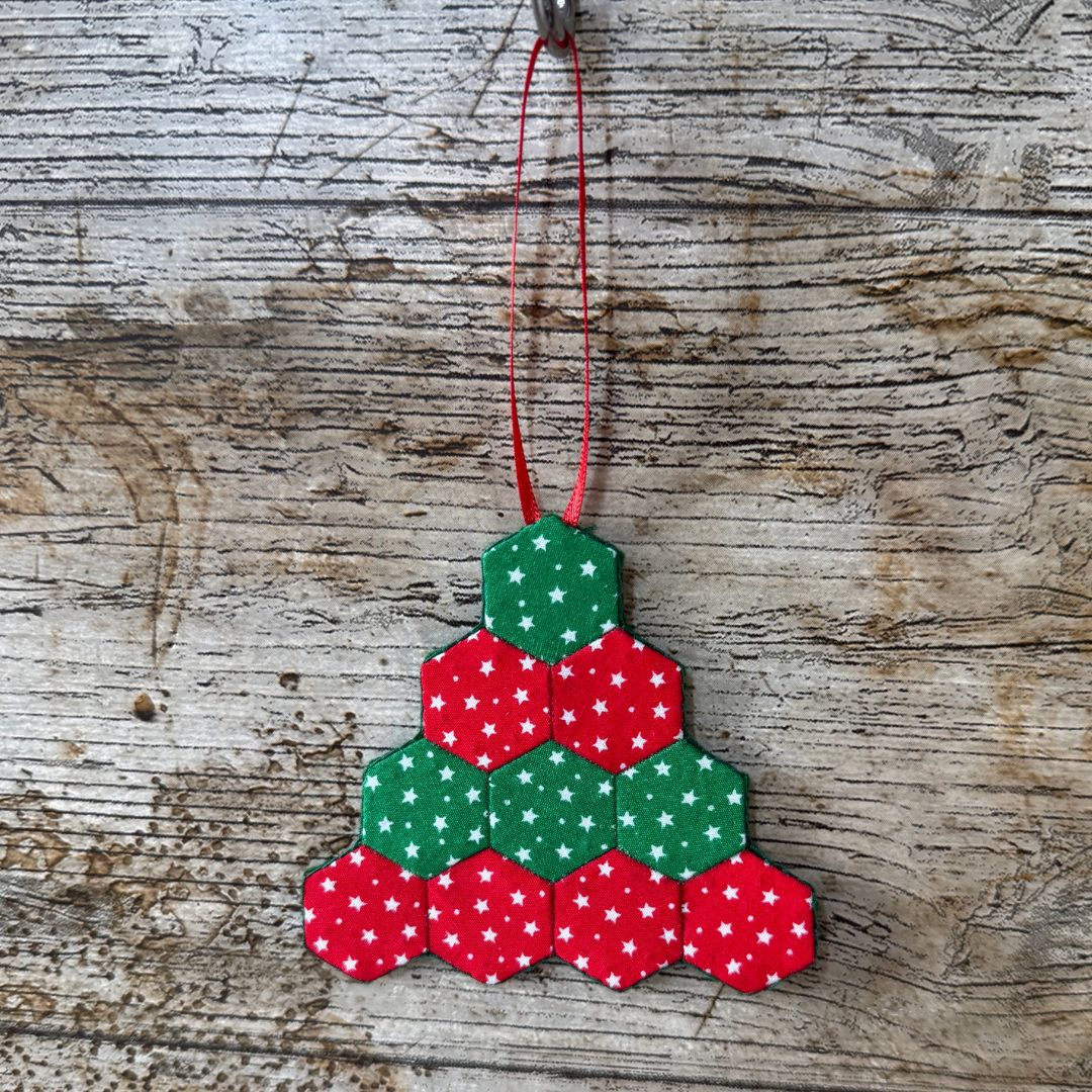 Hexagonal Christmas tree ornament with red and green pattern on a wooden surface