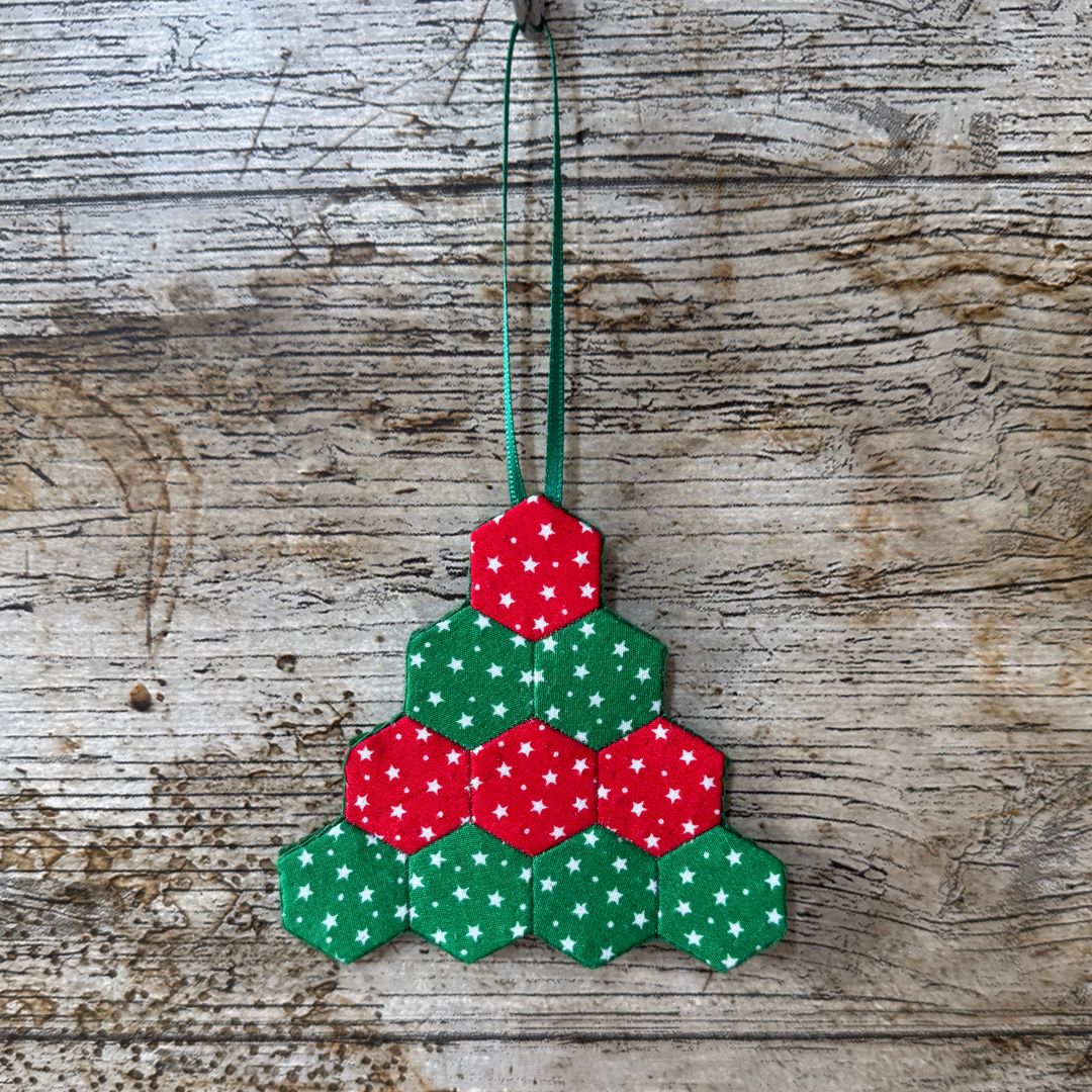 Hexagonal Christmas tree ornament with red and green colors on a wooden background
