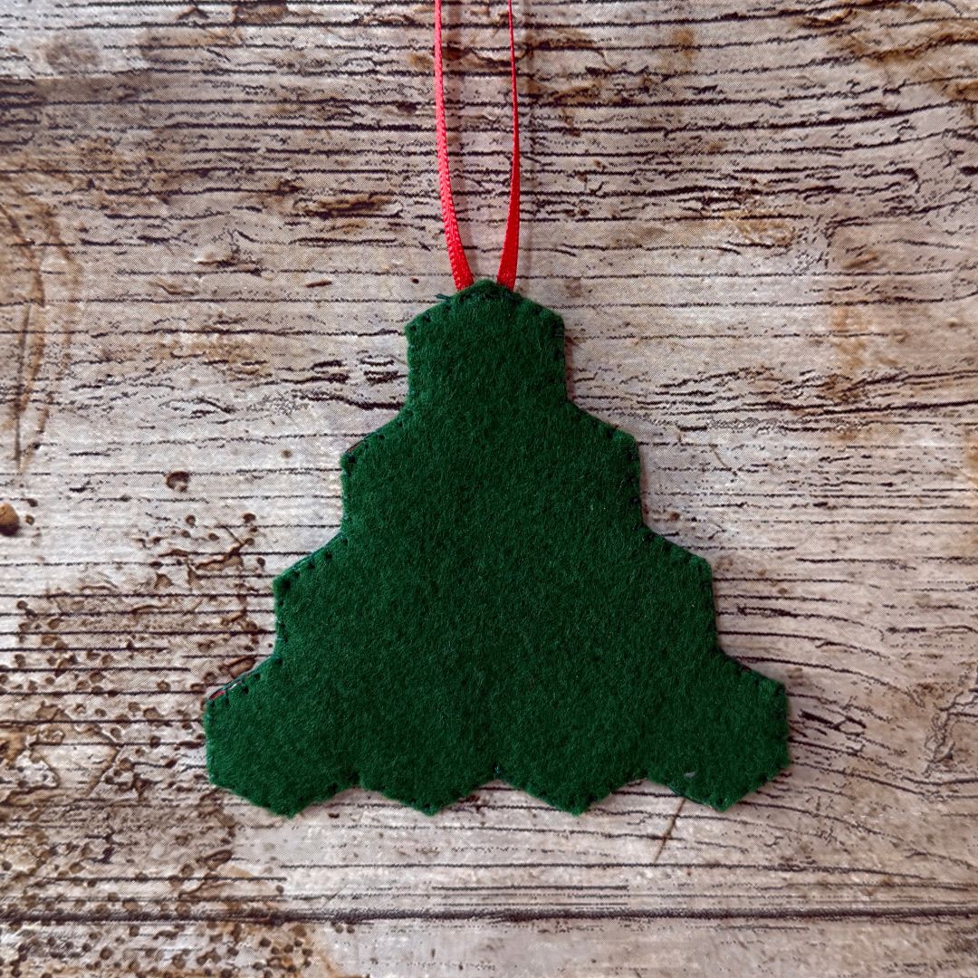Green felt Christmas tree ornament on a wooden surface