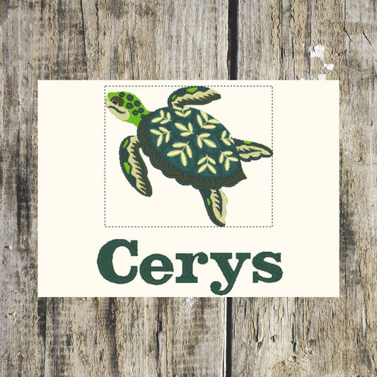 A square cream card or print featuring a green sea turtle illustration above the word 'Cerys' in dark green text, displayed against a rustic weathered wood background.