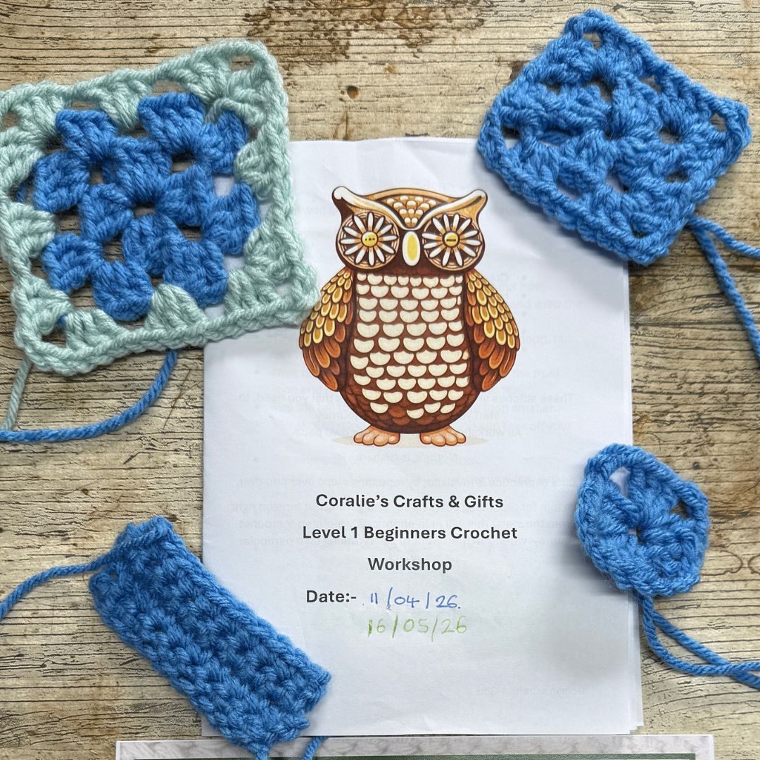 A printed workshop flyer for 'Coralie's Crafts & Gifts Level 1 Beginners Crochet Workshop' is laid on a rustic wooden table, surrounded by several blue and mint green crocheted granny squares and swatches, the results of one students work.