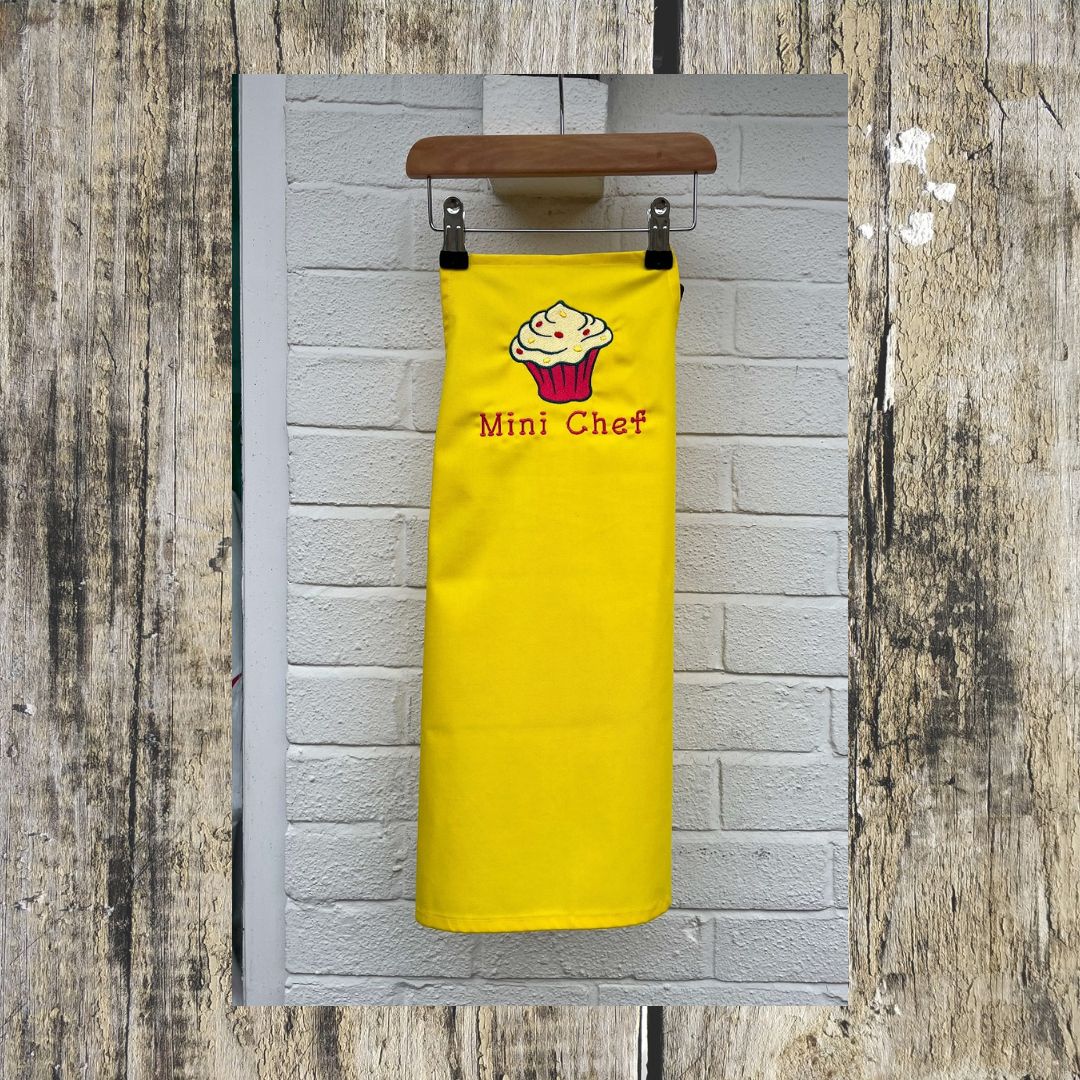 Beautiful Cupcake design is embroidered onto Children's aprons with the wording Mini Chef, Kids apron sizes are ages 3-6 or age 7-10, in this picture is the full length of the apron.