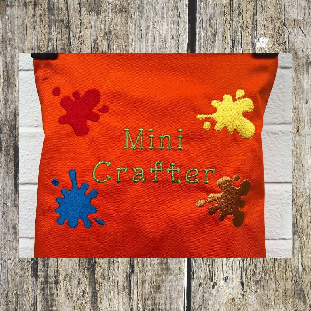 This wonderful orange Mini Crafter Apron has embroidered splodges of paint on it and the wording  Mini Crafter, all embroidered by Coralie at Coralie's Crafts & Gifts.