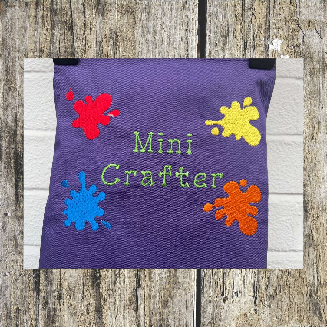 This wonderful Purple Mini Crafter Apron has embroidered splodges of paint on it and the wording  Mini Crafter, all embroidered by Coralie at Coralie's Crafts & Gifts.