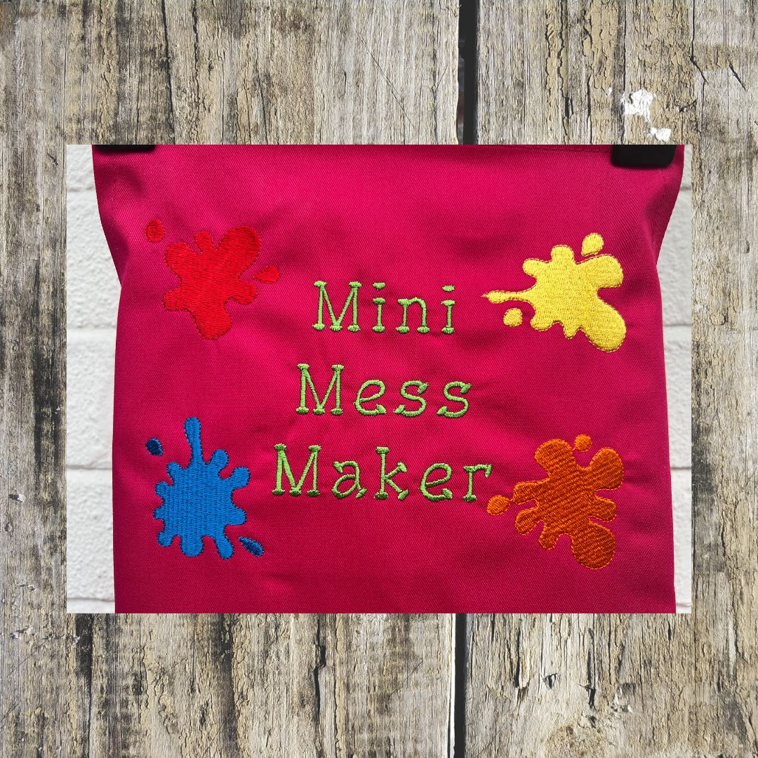 Beautiful hot pink apron, with the mini mess maker apron design embroidered onto it, with funky embroidered splodges of paint on them. 