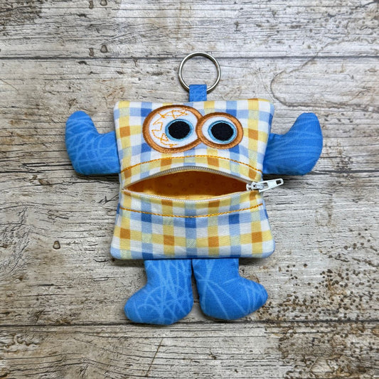 Money monster purse keychain with a checked pattern on a wooden surface