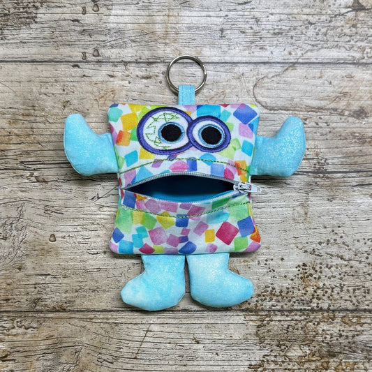 Colourful monster-shaped children's purse with a zipper on a wooden surface