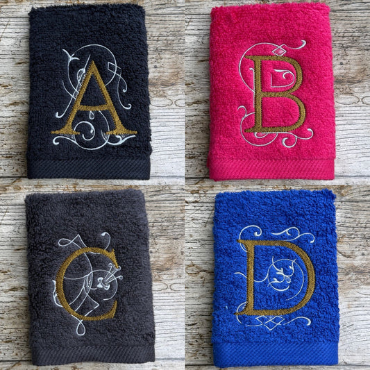 Four embroidered towels with monograms on a wooden surface