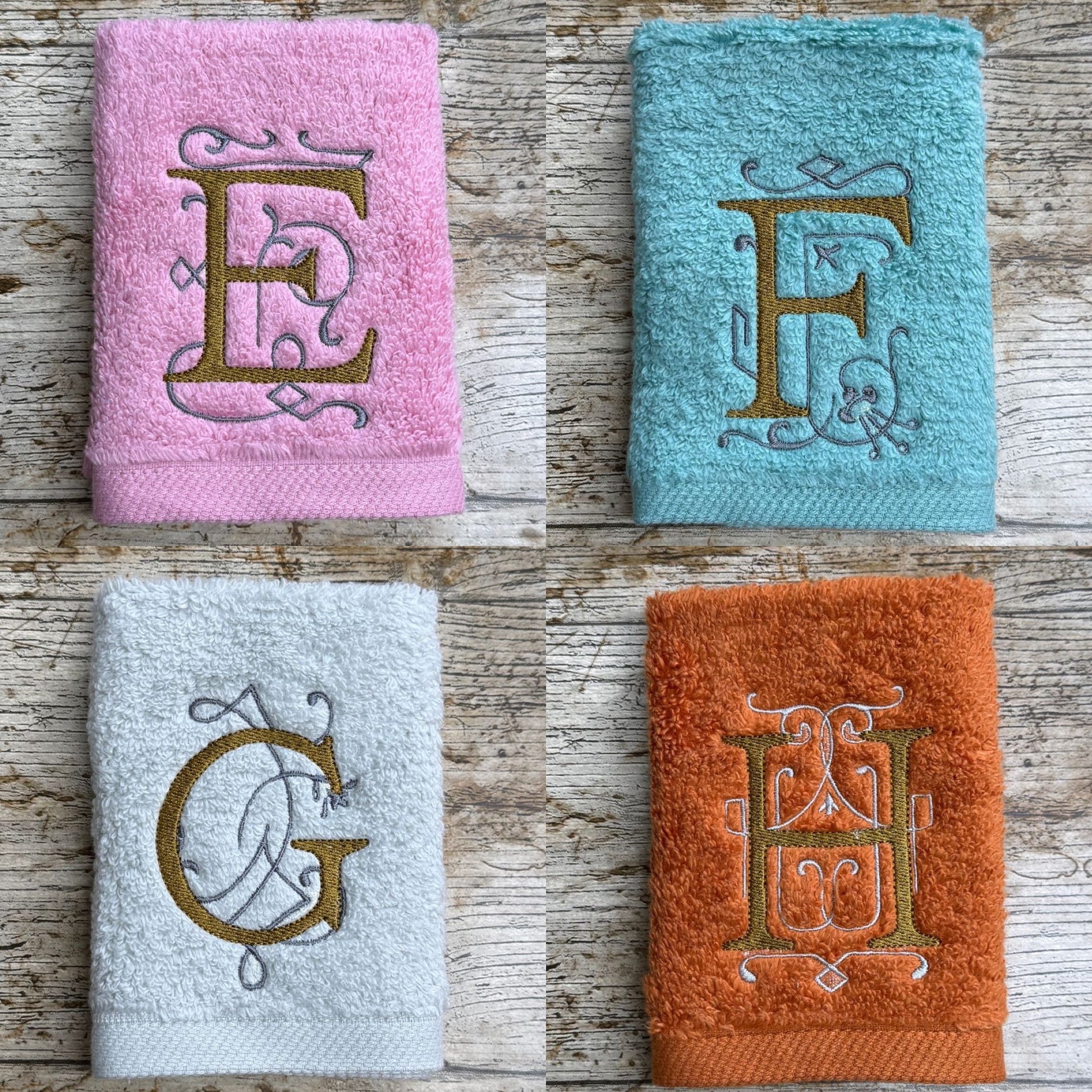 Four towels with embroidered letters on a wooden surface