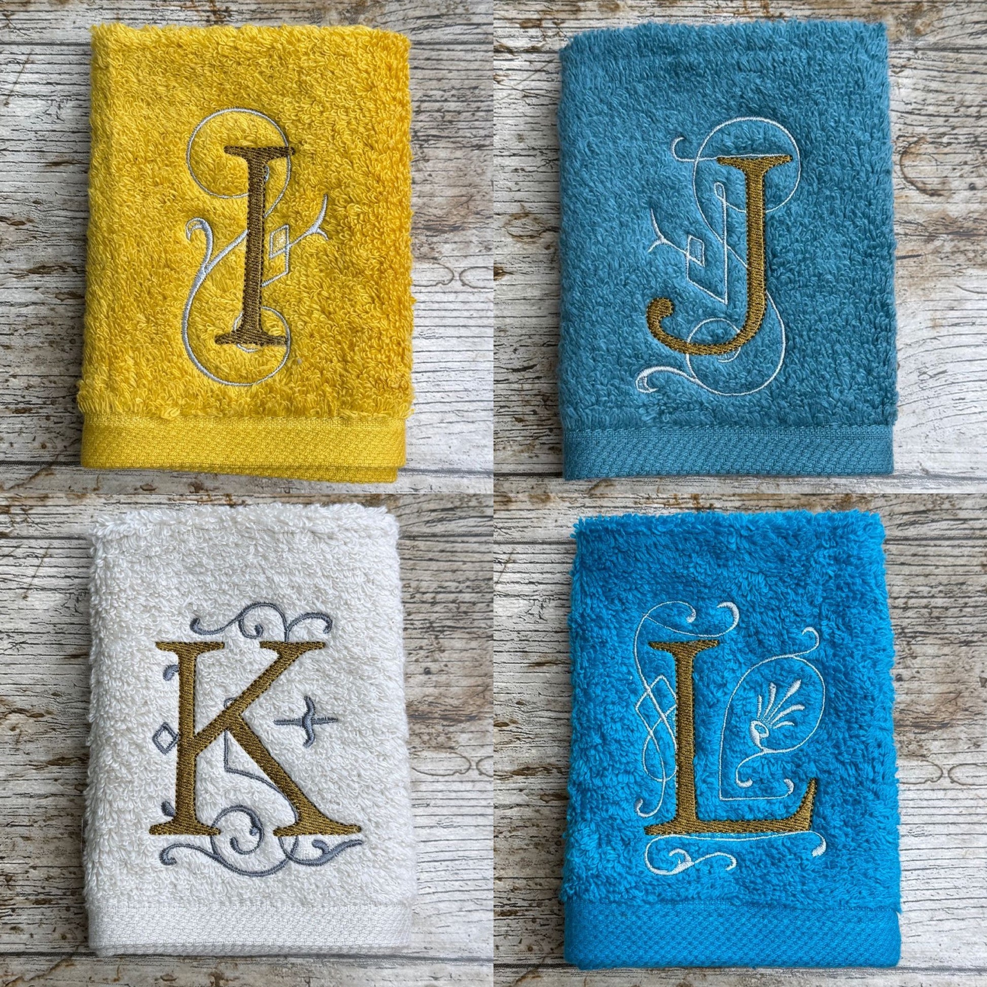 Four towels with embroidered letters on a wooden surface