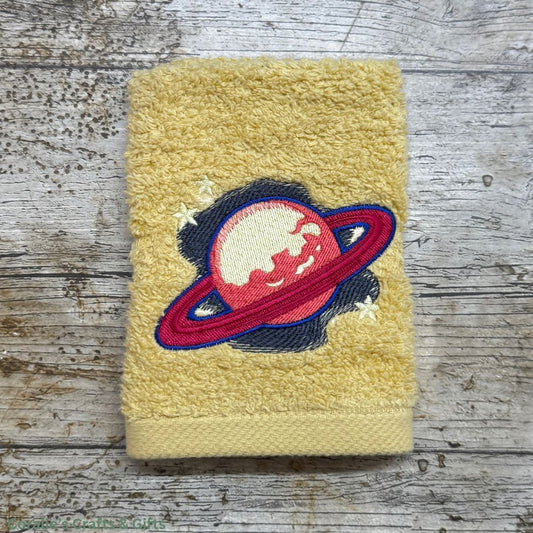 Yellow towel with a planet and ring design on a wooden surface