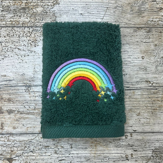 Green towel with a colorful rainbow and star design on a wooden surface