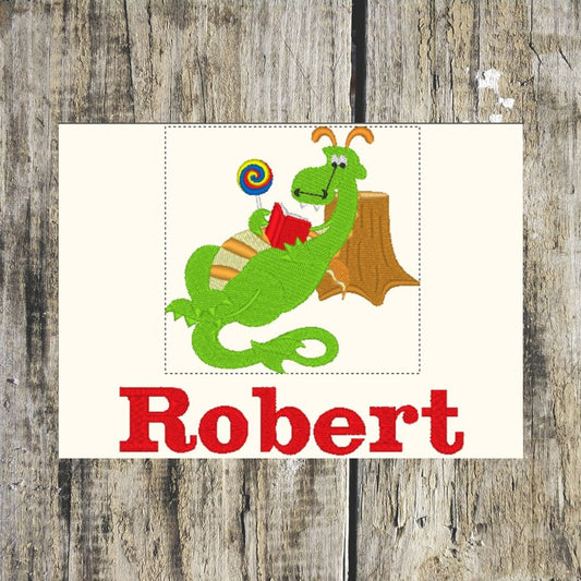 Green dragon holding a lollipop and a book personalised with a name on a wooden background