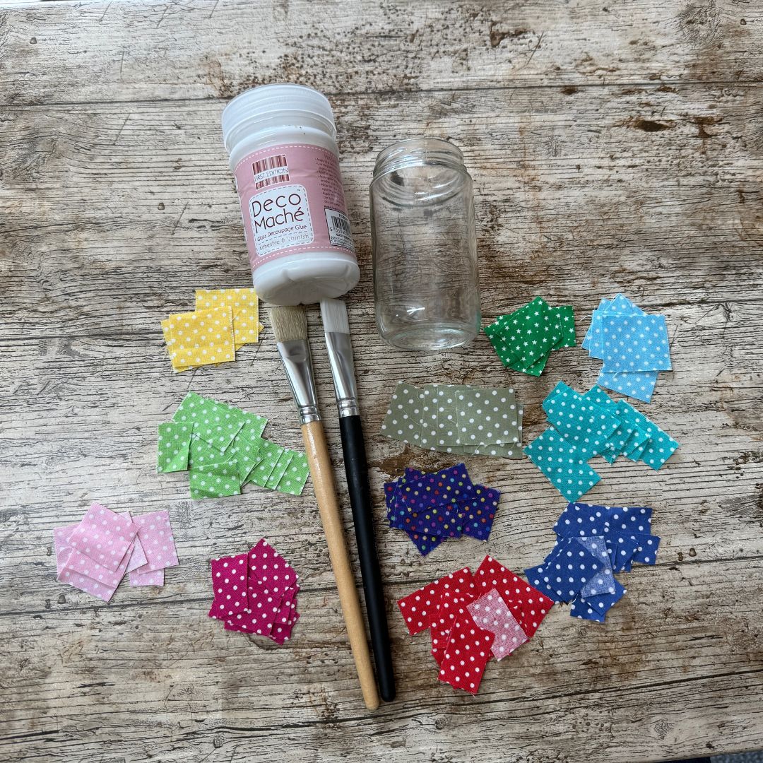 Decoupage Glue bottle, brush, and colourful polka dot fabric pieces on a wooden surface
