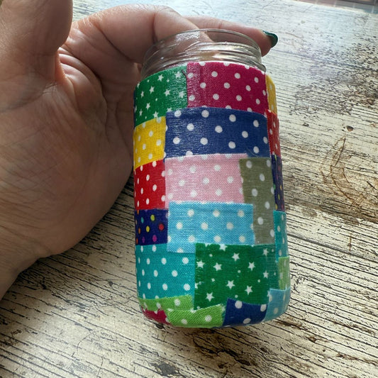 Colorful fabric-wrapped jar displayed a hand on a wooden surface