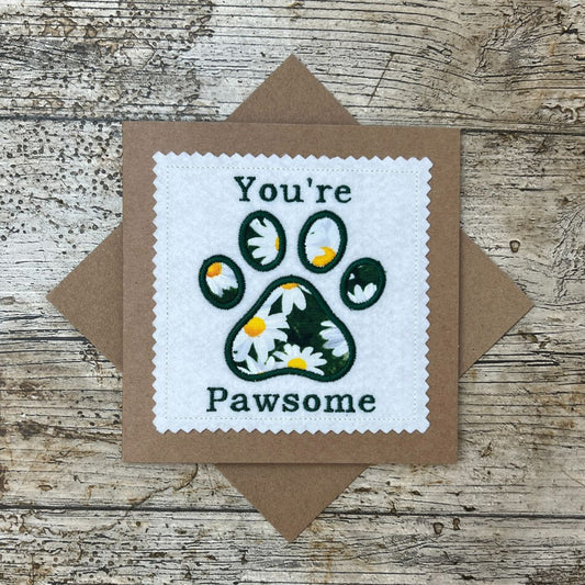 Card with paw print design and text 'You're Pawsome' on a wooden surface
