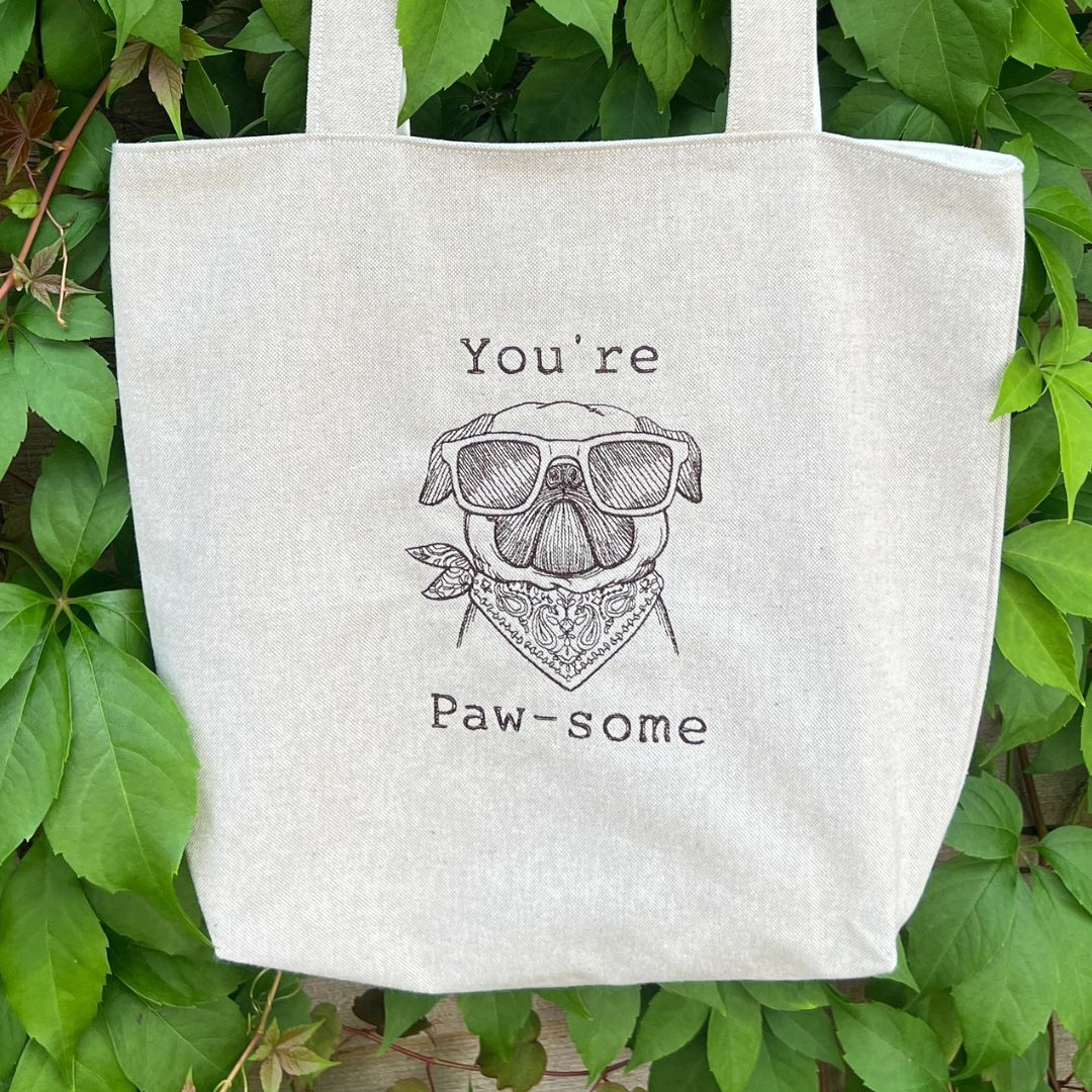 A close up look at the front of the tote bag with "You're Paw-some" design embroidered onto the front. 